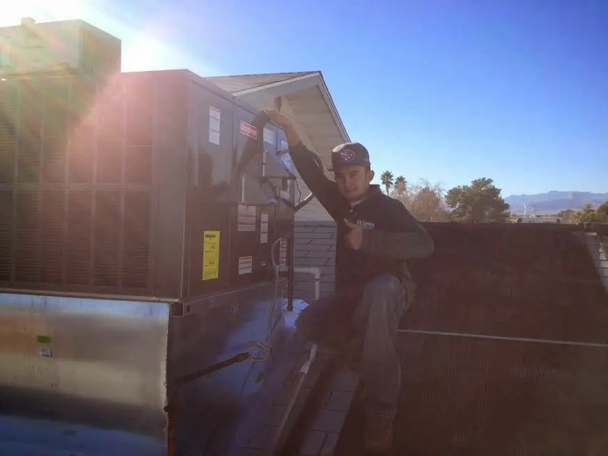 HVAC technician performing Air Duct Cleaning on a rooftop unit in Leander