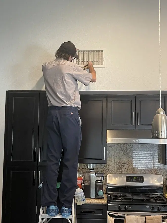 Technician inspecting an air vent during HVAC service in Leander